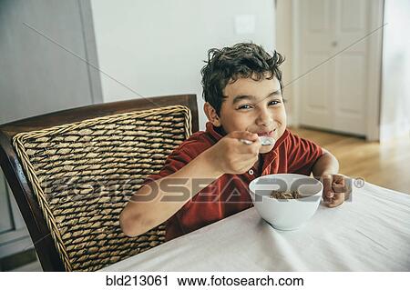 Mixed race boy eating cereal at table View Large Photo Image Stock Image - Mixed race boy eating cereal at table. Fotosearch