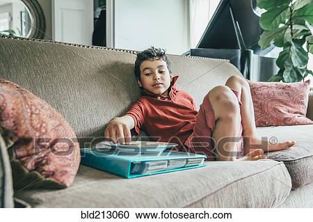 Mixed race boy eating snack on sofa View Large Photo Image Stock Image - Mixed race boy eating snack on sofa. Fotosearch