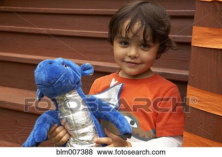 Stock Photo - Mixed race boy holding stuffed dragon. Fotosearch
