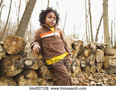 Mixed race boy leaning against firewood View Large Photo Image Stock Photo - Mixed race boy leaning against firewood. Fotosearch