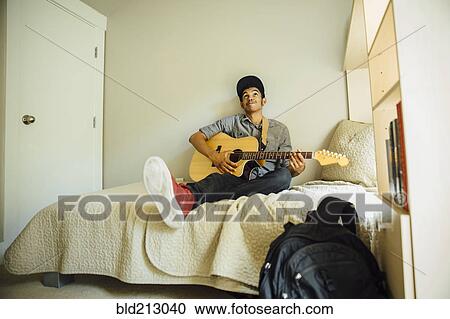 Mixed race boy playing guitar in bedroom View Large Photo Image Stock Image - Mixed race boy playing guitar in bedroom. Fotosearch