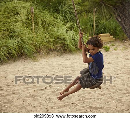 Stock Image - Mixed race boy playing on swing. Fotosearch