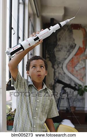 Stock Image - Mixed race boy playing with model rocket. Fotosearch