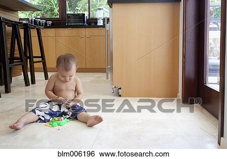 Stock Photograph - Mixed race boy playing with toys on floor. Fotosearch