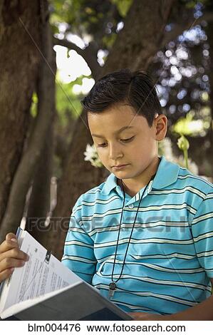 Mixed race boy reading book outdoors View Large Photo Image Stock Photograph - Mixed race boy reading book outdoors. Fotosearch