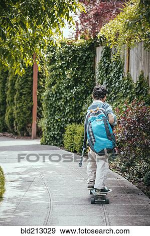 Stock Photo - Mixed race boy riding skateboard on sidewalk. Fotosearch