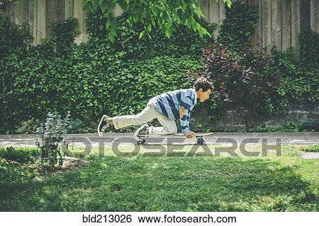 Stock Photograph - Mixed race boy riding skateboard on sidewalk. Fotosearch