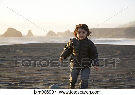 Stock Photo - Mixed race boy running on beach. Fotosearch