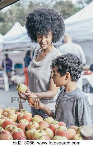 Stock Photograph - Mixed race boy shopping with mother at farmers market. Fotosearch