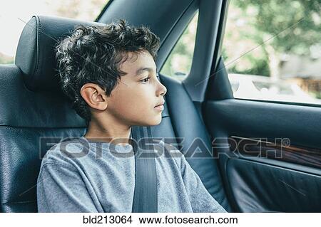 Picture - Mixed race boy sitting in car back seat. Fotosearch