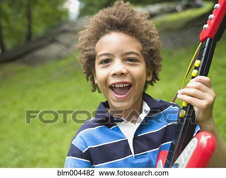 Stock Image - Mixed race boy with plastic guitar. Fotosearch