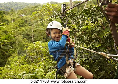 Stock Image - Mixed race boy zip lining. Fotosearch