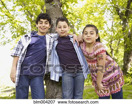 Mixed race boys and girl hugging in front of tree View Large Photo Image Stock Photo - Mixed race boys and girl hugging in front of tree. Fotosearch