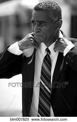 Stock Photography - Mixed race businessman adjusting jacket. Fotosearch