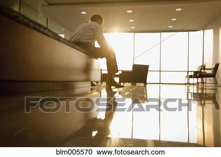 Stock Image - Mixed race businessman sitting in lobby. Fotosearch