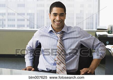 Stock Photography - Mixed race businessman sitting on desk. Fotosearch