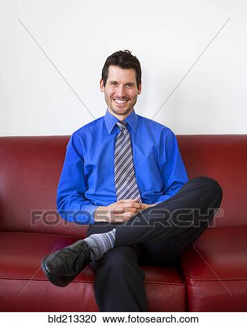 Stock Image - Mixed race businessman smiling on sofa. Fotosearch