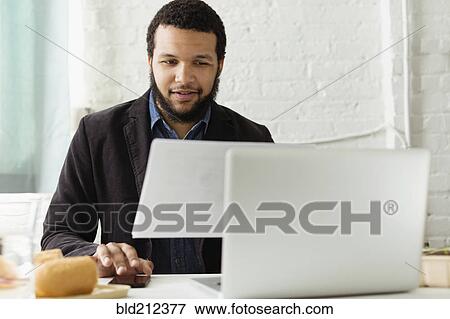 Stock Photo - Mixed race businessman working at desk. Fotosearch