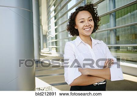 Stock Image - Mixed race businesswoman standing on city street. Fotosearch
