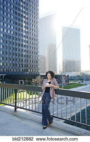 Mixed race businesswoman using cell phone on urban sky bridge View Large Photo Image Stock Image - Mixed race businesswoman using cell phone on urban sky bridge. Fotosearch