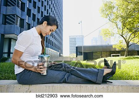 Stock Image - Mixed race businesswoman using tablet computer in city. Fotosearch