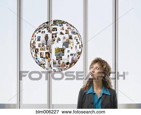 Stock Photo - Mixed race businesswoman with floating globe of faces. Fotosearch