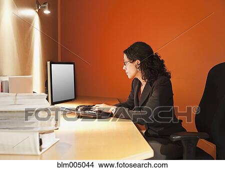 Picture - Mixed race businesswoman working at desk. Fotosearch
