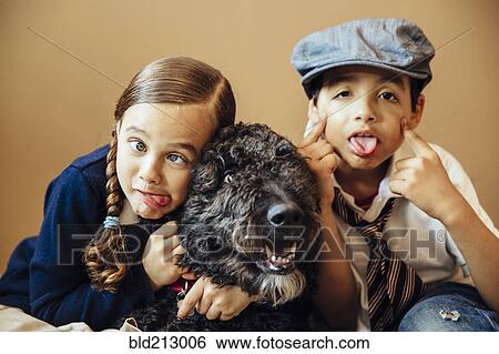 Stock Photograph - Mixed race children making faces with dog. Fotosearch