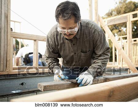 Mixed race construction worker measuring lumber View Large Photo Image Stock Photo - Mixed race construction worker measuring lumber. Fotosearch