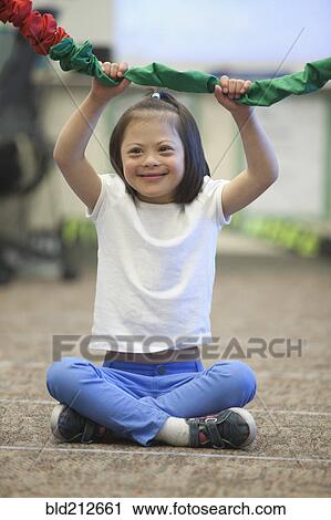 Stock Image - Mixed race Down syndrome girl playing with rope. Fotosearch