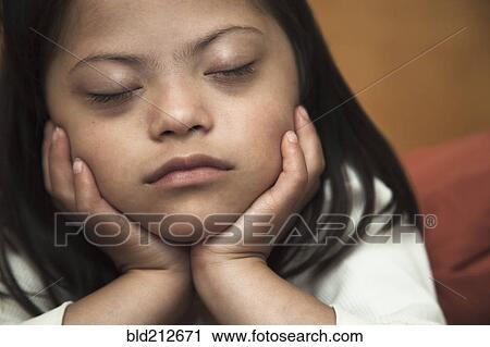 Stock Image - Mixed race Down syndrome girl resting with chin in hands. Fotosearch