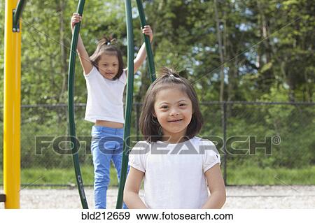 Stock Photo - Mixed race Down syndrome girls smiling on playground. Fotosearch