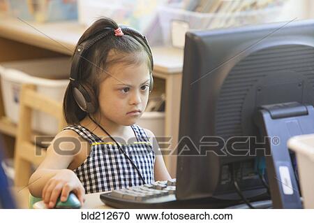 Stock Image - Mixed race Down syndrome student using computer. Fotosearch
