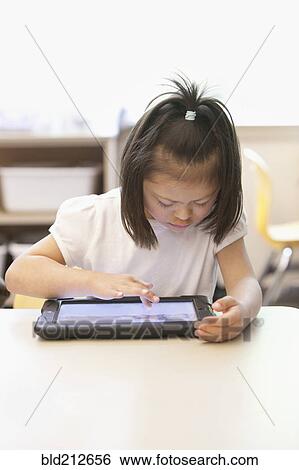 Mixed race Down syndrome student using tablet computer in classroom View Large Photo Image Stock Photograph - Mixed race Down syndrome student using tablet computer in classroom. Fotosearch
