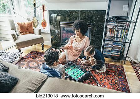 Mixed race family playing foosball on living room floor View Large Photo Image Stock Photo - Mixed race family playing foosball on living room floor. Fotosearch