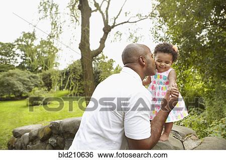 Mixed race father kissing daughter in park View Large Photo Image Stock Photograph - Mixed race father kissing daughter in park. Fotosearch