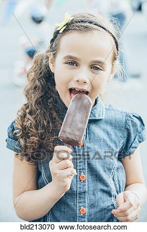 Mixed race girl eating fudgesicle on city street View Large Photo Image Stock Image - Mixed race girl eating fudgesicle on city street. Fotosearch