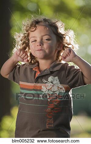 Stock Image - Mixed race girl grimacing with arms raised. Fotosearch