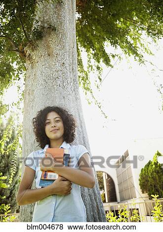 Mixed race girl holding books outdoors View Large Photo Image Stock Photo - Mixed race girl holding books outdoors. Fotosearch