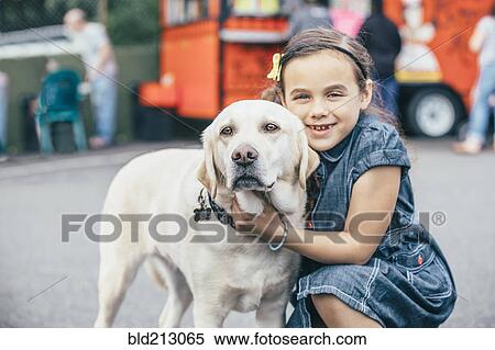 Stock Photography - Mixed race girl hugging dog on street. Fotosearch