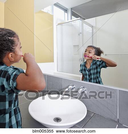 Stock Photography - Mixed race girl in bathroom brushing teeth. Fotosearch