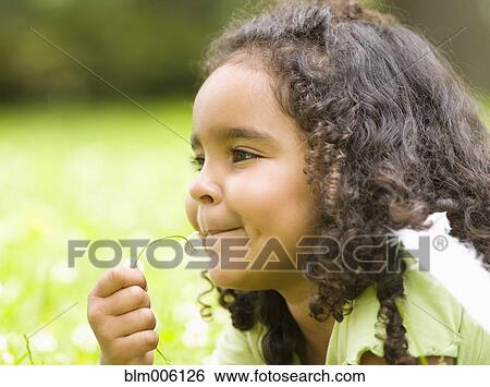 Stock Photograph - Mixed race girl laying in grass. Fotosearch
