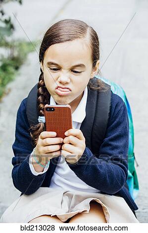 Mixed race girl making a face at cell phone View Large Photo Image Stock Photo - Mixed race girl making a face at cell phone. Fotosearch