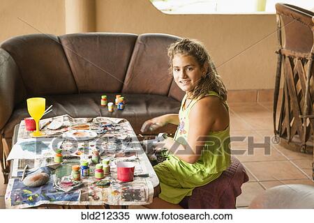 Stock Photography - Mixed race girl painting at coffee table. Fotosearch