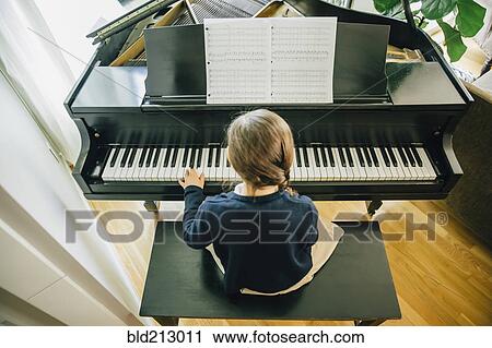 Stock Image - Mixed race girl playing piano. Fotosearch