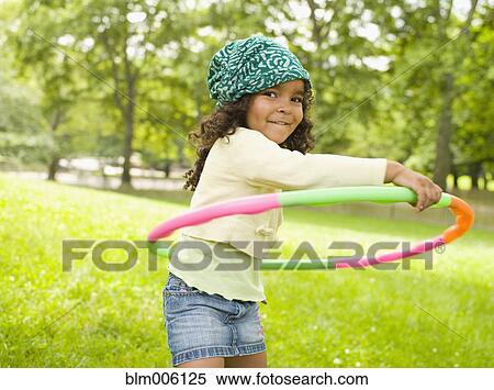 Stock Photography - Mixed race girl playing with plastic hoop. Fotosearch