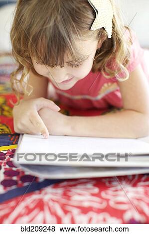 Stock Photo - Mixed race girl reading on bed. Fotosearch