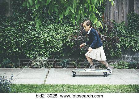 Stock Photography - Mixed race girl riding skateboard on sidewalk. Fotosearch