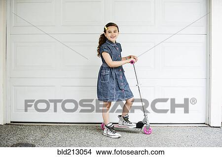 Mixed race girl smiling on scooter in driveway View Large Photo Image Picture - Mixed race girl smiling on scooter in driveway. Fotosearch