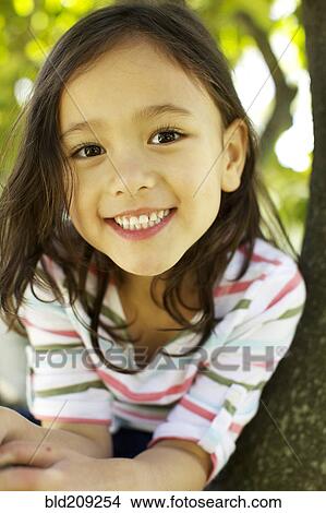 Picture - Mixed race girl smiling outdoors. Fotosearch